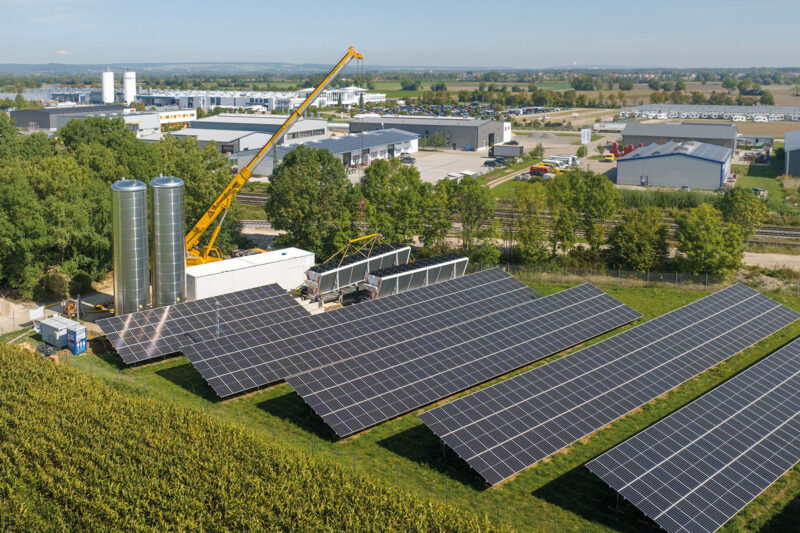 Luftbild einer Heizzentrale aus Photovoltaik-Freiflächenanlage und Luftwärmepumpe mit zwei Speichern in Mertingen.