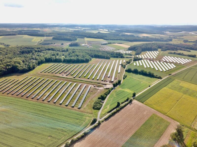 Luftbild eines Solarparks in grüner Umgebung.