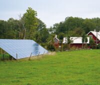 Garten-PV-Anlage vor einem roten Holzhaus