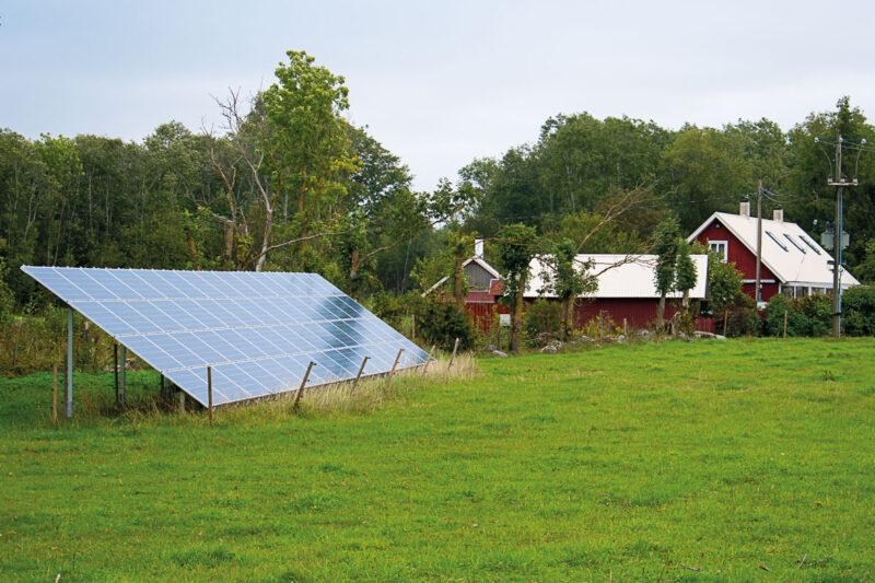 Garten-PV-Anlage vor einem roten Holzhaus