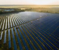 Luftbild eines Freiflächensolarparks bei tief stehender Sonne