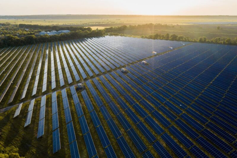 Luftbild eines Freiflächensolarparks bei tief stehender Sonne