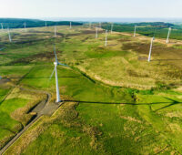 Luftaufnahme mit Windpark auf grünem Land - Windenergie in Irland. Batteriespeicher zur Netzstabilität sind dabei auch gefragt.