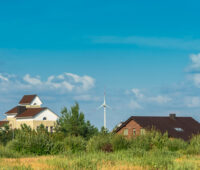 Einige Häuser, im Hintergrund Windkraftanlagen