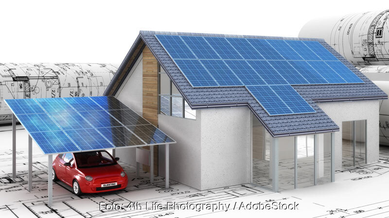 Modell eines Einfamilienhauses mit Solardach und SOlar-Carport auf Bauplänen.