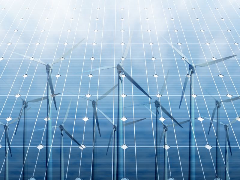 Windkraftanlagen reflektieren auf blauen Solarmodulen.