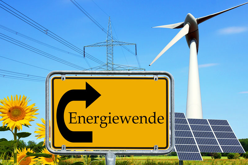 Fotomontage: Ortsschild Energiewende mit Photovoltaik, Windrad , Sonnenblume und Strom-Freileitung