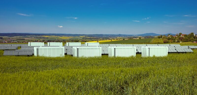 Fotomontage zeigt PV-Park mit Speichern auf grüner Wiese.