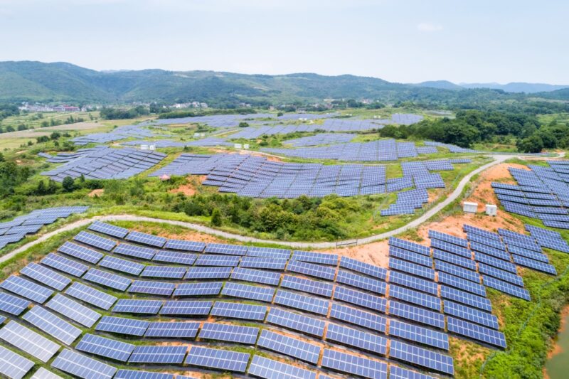 PV-Freiflächen über einer grünen Hügellandschaft in China.