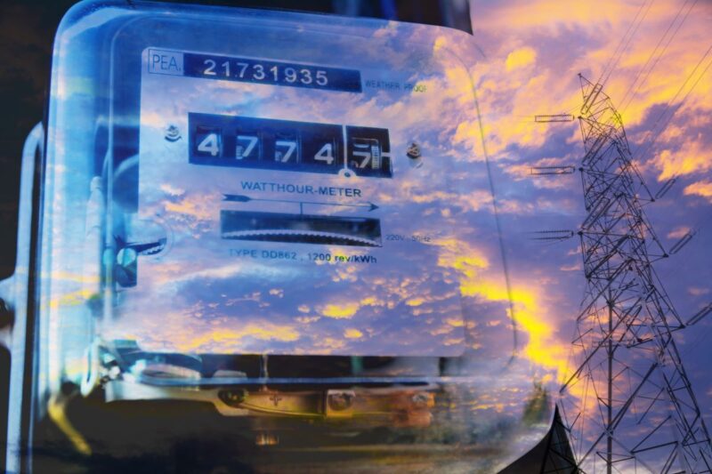 Foto durch Glas zeigt einen Stromzähler außerdem die Reflexion der Wolken und eines Strommastes.