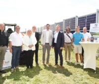 Menschengruppe neben senkrechten Solarmodulen.