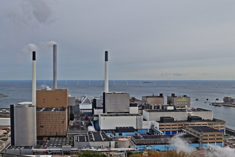 Müllkraftwerk von Kopenhagen-Amager mit rauchenden Abgasschloten am Meer.
