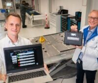 Zu sehen sind die Audi-Mitarbeiter Robin Krause und Joachim Wöhle, die mit Battman ReLife E-Auto-Batterien auf ihre Tauglichkeit zum Second Lift testen.