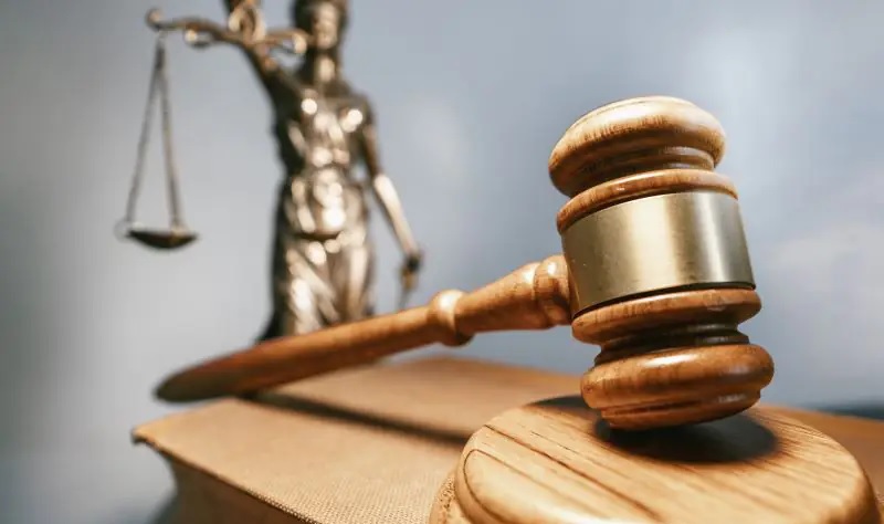 Im Bild Justitia hinter einem Tisch mit Richterstab als Symbol für das Urteil zur Preisanpassungsklauseln der Fernwärmeversorger.