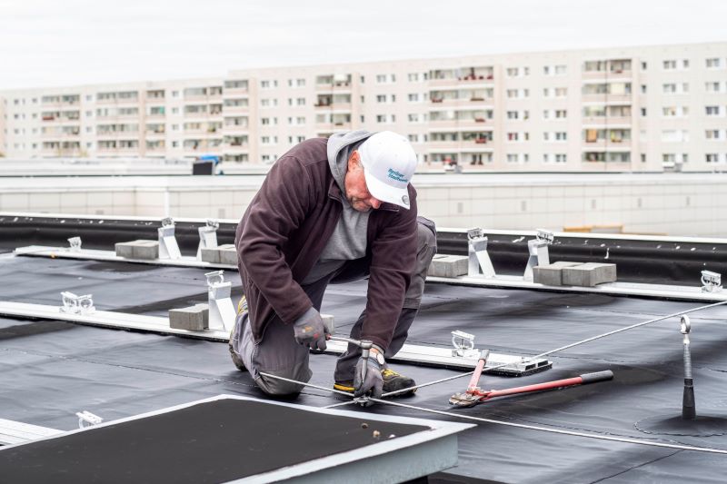 Ein Mann montiert auf einem Hochhausdach Bahnen für Solarmodule.