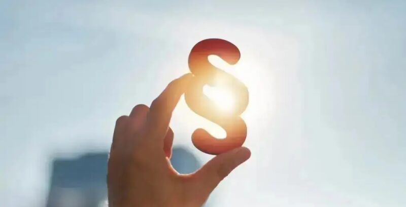 Im Bild ein Paragrafenzeichen, das eine Hand in die Sonne hält als Symbol für das Solarpaket I, das in Kraft getreten ist.