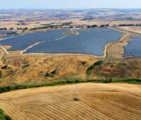 Luftbild zeigt Freiflächensolarpark in trockener, hügeliger Landschaft.