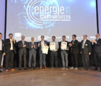 Auf einer Bühne stehen zehn Personen und präsentieren Urkunden vom Byrischen Energiuepreis 2018 für Start-Ups.