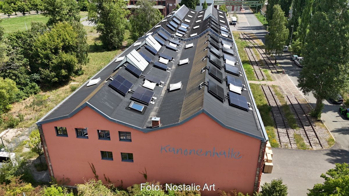 Alte Industriehalle mit PV-Modulen auf dem M-förmigen Dach.