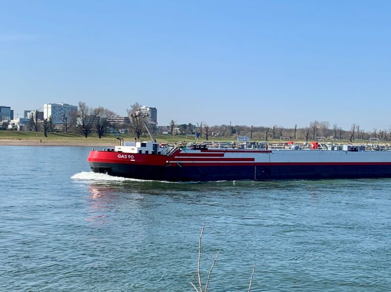 Ein Binnenschiff fährt auf dem Rhein bei blauem Himmel.