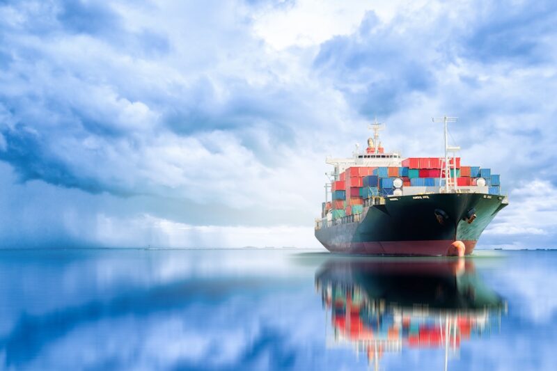 großes Containerschiff auf ruhigem meer mit wolkigem Himmel - Symbol für Biokraftstoff für Seetransport.