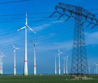 Windenergie-Anlagen und Strommast. Symbolbild für die Ausschreibung für Windenergie an Land.