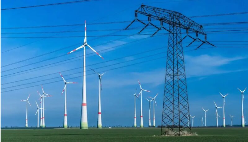 Windenergie-Anlagen und Strommast.