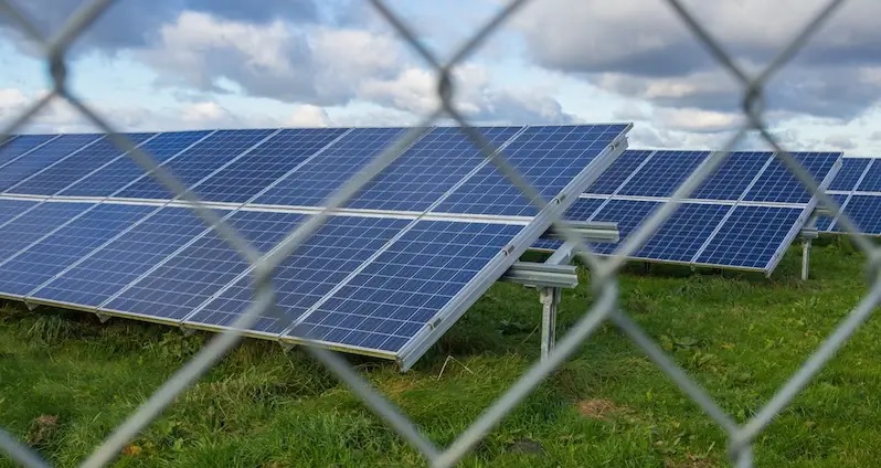 Zu sehen ist eine eingezäunte PV-Großanlage als Symbol für die Verschleppung der Ausbaupfade für Photovoltaik und Windenergie durch die Bundesregierung.