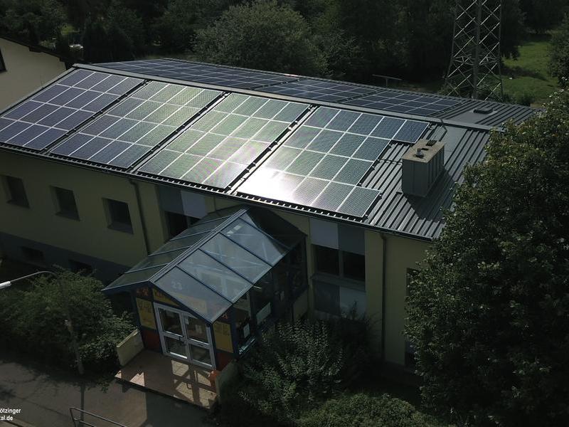 Eine Solaranlage auf dem Dach einer Kita bei tiefstehender Sonne,
