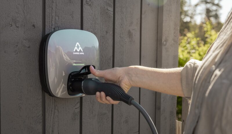 Im Bild eine Hand, die das Ladekabel in die Wallbox Charge Amp Luna steckt.