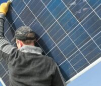 Ein Handwerker hat ein Solarmodul auf der Schulter, die Schweizer Constellation Energy hat den saarländischen PV-Installateur Sonalis übernommen.