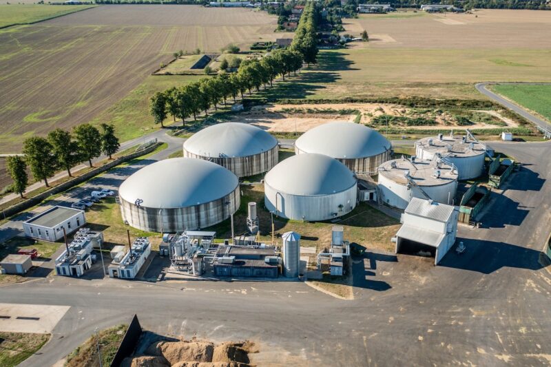 Das Bild zeigt eine Biogasanlage mit mehreren Gebäuden aus der Luftsicht.