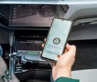 Hand hält Smartphone in einem Auto - Batterie-Schnelltest für Elektro-Autos bei der Dekra