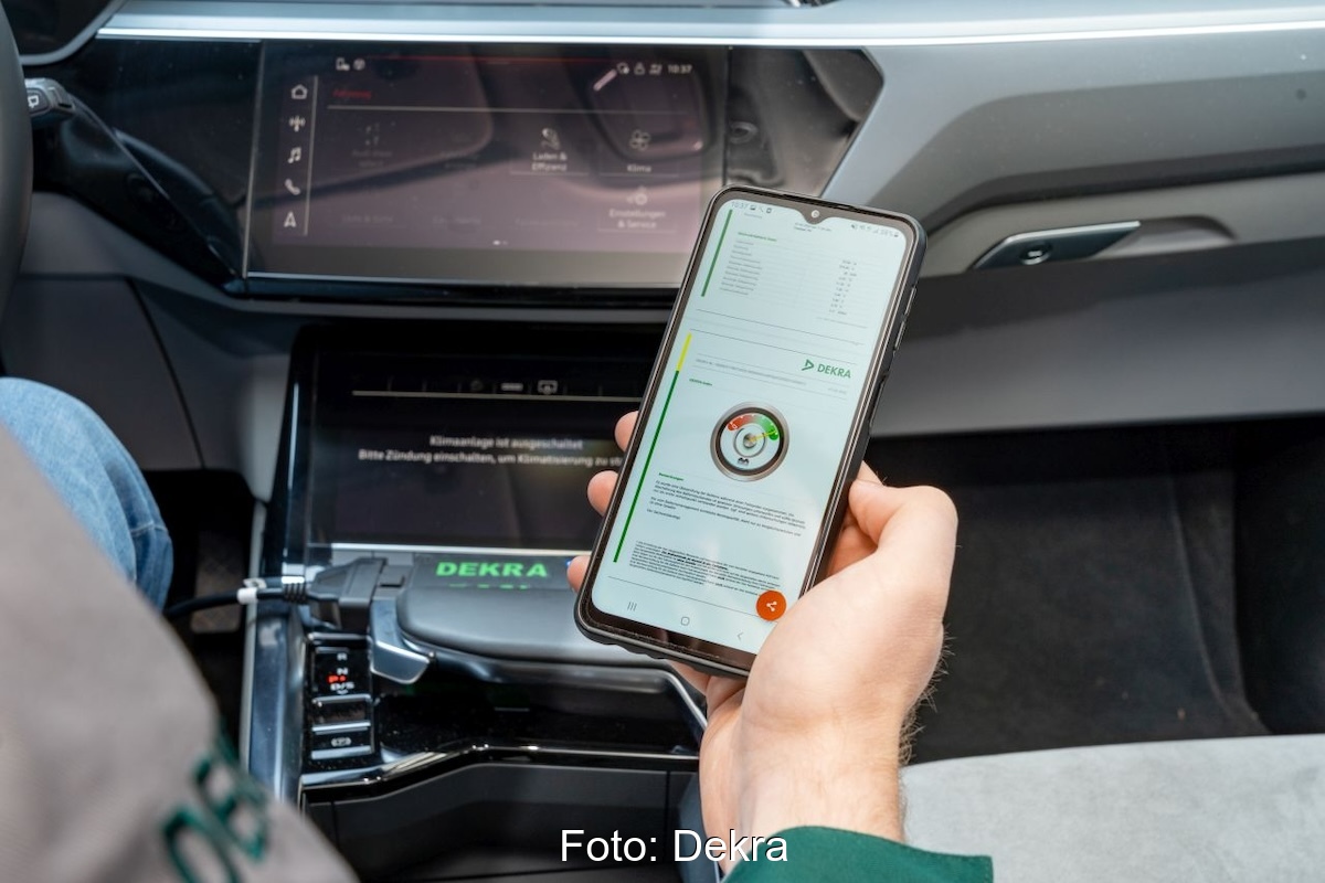 Hand hält Smartphone in einem Auto - Batterie-Schnelltest für Elektro-Autos bei der Dekra