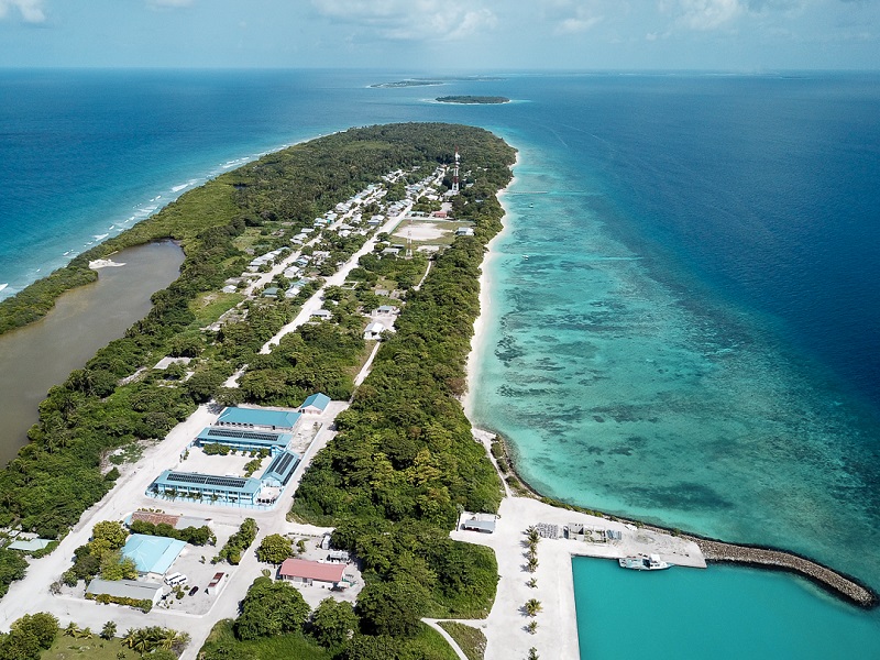 Zu sehen sind vernetzte Photovoltaik-Microgrids auf einer Luftaufnahme einer Insel der Malediven im blauen Ozean.