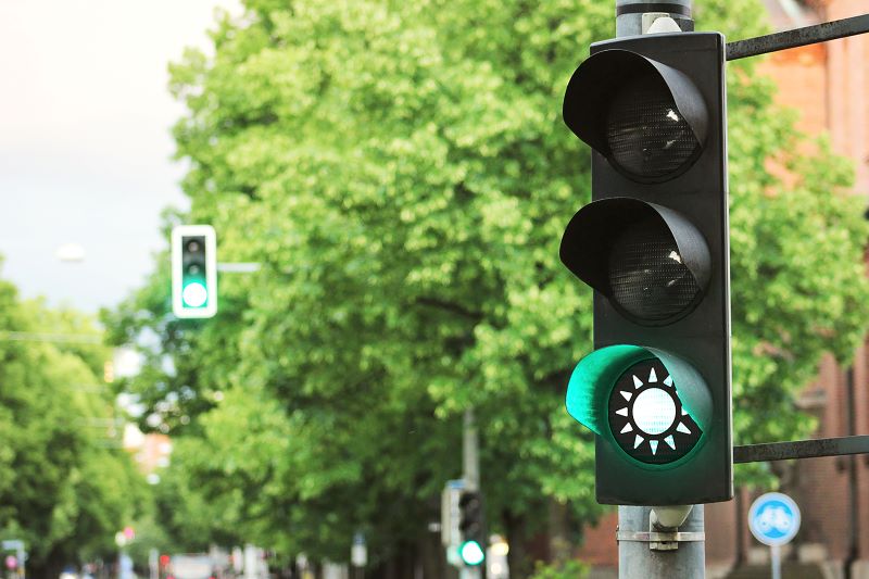 Eine Straßenampel zeigt grün mit dem Symbol einer Sonne.