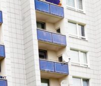 Zu sehen ist ein Geschosswohnungsbau mit vielen kleinen Stecker-Photovoltaik-Anlagen an den Balkonen.