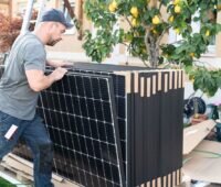 Im Bild ein Mann mit PV-Modulen, Enpal hat sich 5 Milliarden Euro Finanzierung gesichert.