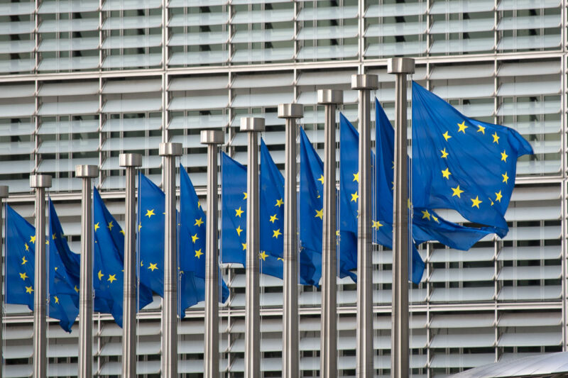 Reihe von wehenden Europaflaggen vor dem Hauptgebäude der EU-Kommission in Brüssel.