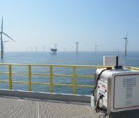 Zu sehen ist ein Lasergerät mitten im Offshore-Windpark, mit dessen Hilfe die Leistung von Offshore-Windparks exakter vorhersehbar werden soll.