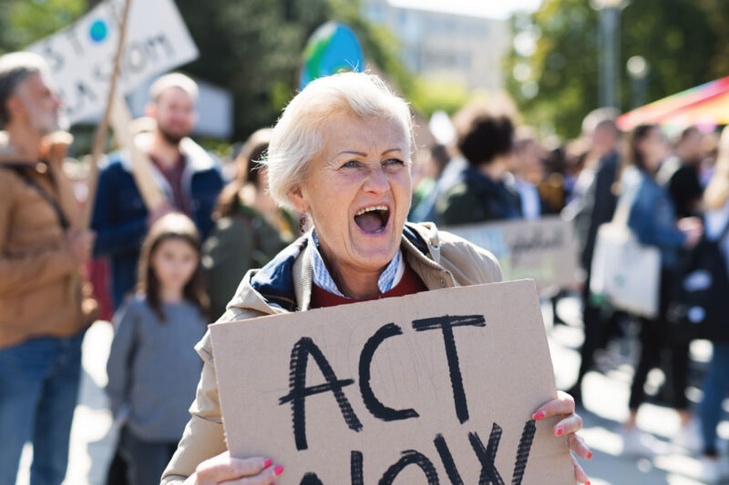 Frau mit Pappschild "Act now" - Symbol für Klimaklage der DUH gegen die Bundesregierung.