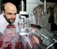 Das Bild zeigt einen Wissenschaftler der die Rolle-zu-Rolle-Anlage für die Produktion von Membranen für Brennstoffzellen betrachtet.
