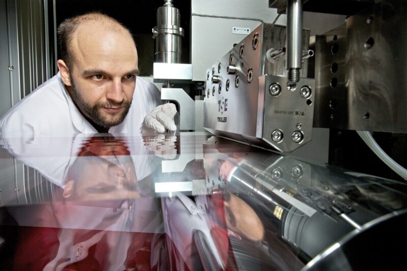 Das Bild zeigt einen Wissenschaftler der die Rolle-zu-Rolle-Anlage für die Produktion von Membranen für Brennstoffzellen betrachtet.