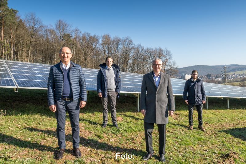 Vier Personen auf grüner hügeliger Wiese mit Photovoltaik .