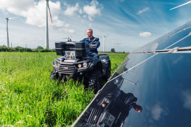 Ein Mann auf einem Quad fährt entlang eines PV-Feldes.