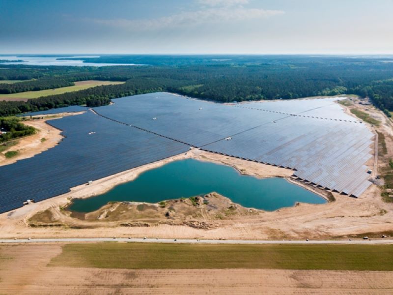 Luftaufnahme eines großen PV-Parks mit angrenzendem See einer Kiesgrube.