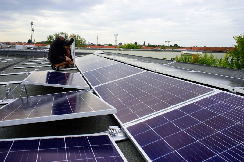 Monteure befestigen Solarmodule auf einem Flachdach. eines hohen Gebäudes.