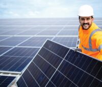 Im Bild ein Handwerker, der ein PV-Modul installiert, der Solar Module Quality Standard SMQS soll langfristige Energieerträge der Solaranlagen sicherstellen.