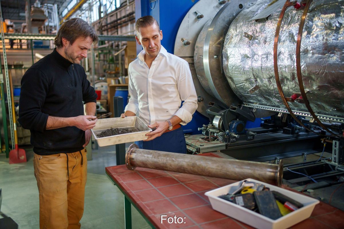 Zwei Männer in einem Industriegebaäude mit Werkstoffen und der schwarzen Masse alter Batterien.