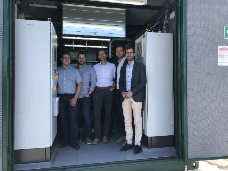 Fünf Männer stehen in einem Container für ein Wasserstoff-BHKW